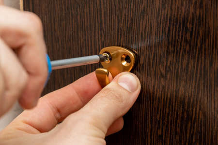 screwing the clothes hook to the wardrobe wall with a screwdriverの写真素材