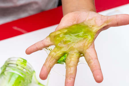 Child playing with red color slime, gunge, gel in handsの写真素材