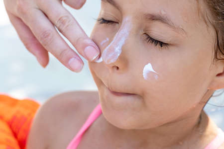 Applying sunscreen cream to the face of a small child, sun and ultraviolet protectionの写真素材