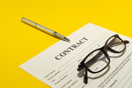 The contract on the yellow table, notebook, glasses and pen.