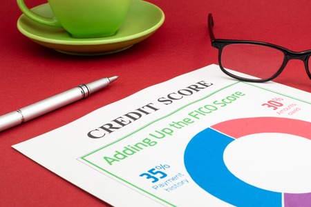 Credit score report with pen and notepad on a red table.
