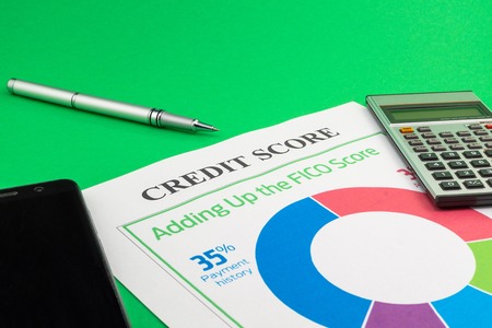 Credit score report with pen, calculator and smartphone on a green table.の写真素材