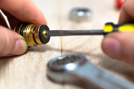 The plumber changes the gasket on the valve of the crane with a screwdriver close-up.の写真素材