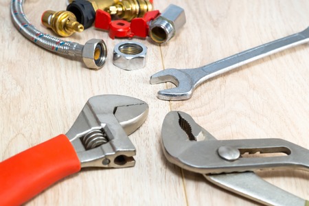 Plumbing tools and replacement parts on a wooden table.の写真素材