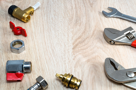 Plumbing tools and replacement parts on a wooden table.の写真素材