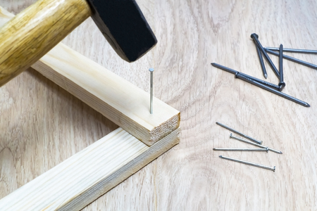 Hammer to hammer a nail into a wooden bar close-up.