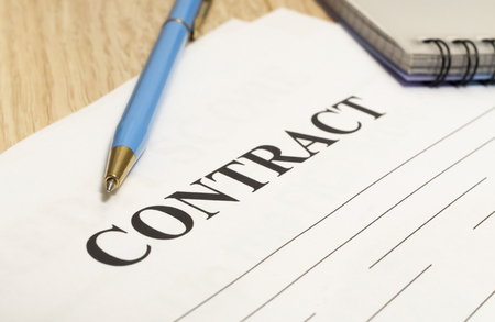 Contract on paper with pen and notebook on wooden table close-up.の写真素材