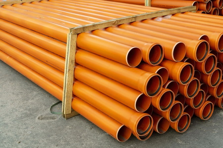 Orange plastic pipes for plumbing or water stacked on a pallet.の写真素材