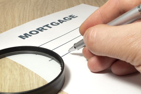 Empty form to fill mortgage with hand, magnifying glass and pen on the table close-up.