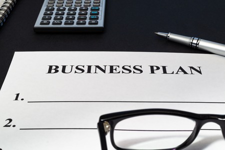 Strategy business plan with calculator, pen and notebook on dark table close up.の写真素材