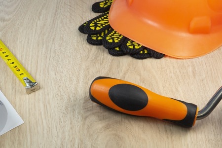 Protective helmet, gloves, tape measure and tool on a wooden table with space for advertising.