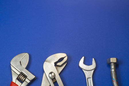 Necessary set of tools for plumbers on a blue background with empty space for advertising.