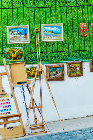 Art equipment: easel, brushes, tubes of paint, palette and paintings on the street.の写真素材