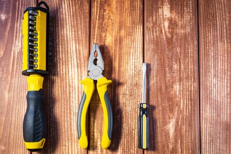 A set of tools for the electrician on a wooden background: screwdrivers, pliers, electrical tape, tester.の写真素材