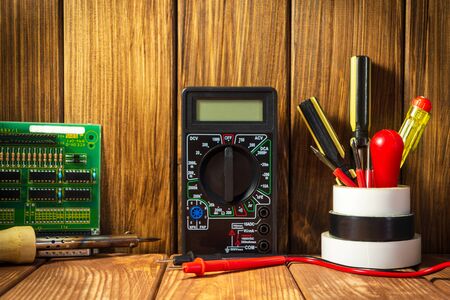 Electrical tester and a set of tools for electronics repair on vintage wooden background.の写真素材
