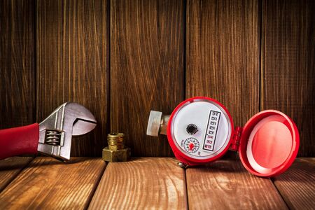 New water meter with fittings and wrench on a vintage wooden background.の写真素材