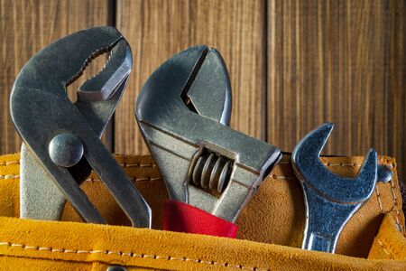 Tools and instruments in leather bag isolated on vintage wooden