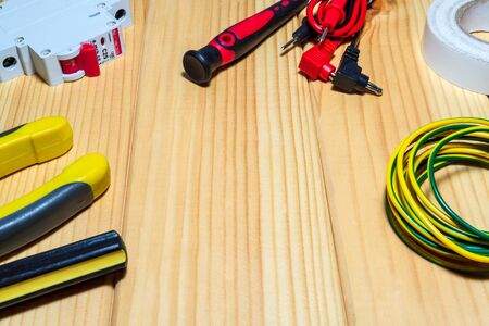 Tools and spare parts for electrician - wiring, tester, screwdrivers on wooden boards.