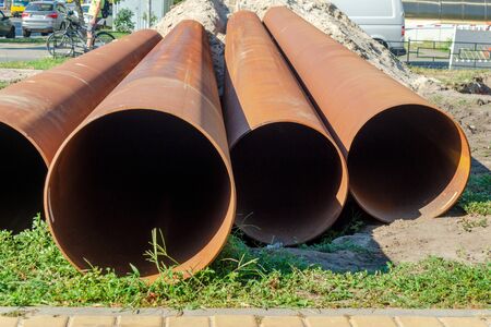 Several metal pipes lying on the street for laying sewage. Industrial material.