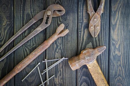 Rusty old tools are laid out on black vintage wood