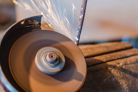 Worker sawing metal with electrical saw, lot of sparks fly from the instrument.