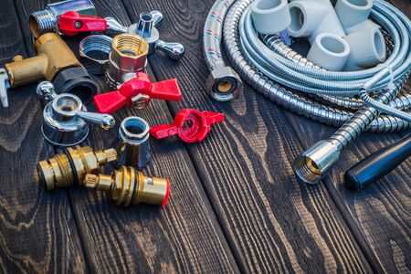 Necessary set of tools and spare parts for plumbers on dark vintage wooden background indispensable...