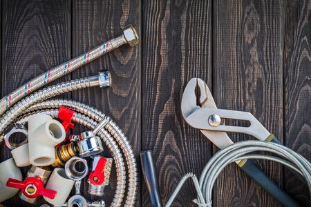 Necessary set of tools and spare parts for plumbers on dark vintage wooden background indispensable for masterの写真素材