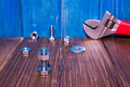 Metal bolt and nut on vintage wooden background with adjustable wrenchの写真素材