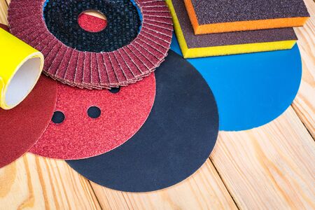 Set of abrasive tools different colors and sandpaper on wooden background. The wizard is used for grinding itemsの写真素材