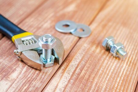 Metal bolt and nut on brown vintage wooden background with adjustable wrench for the masterの写真素材