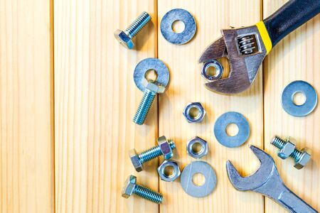 Metal bolts and nuts on wooden background with adjustable wrench for the masterの写真素材