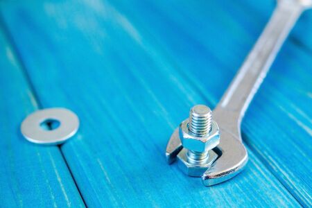 Metal bolts and nuts on blue wooden background with adjustable wrench for the masterの写真素材