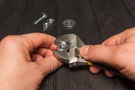 Master hands tightens the nut with an adjustable wrench on a black background