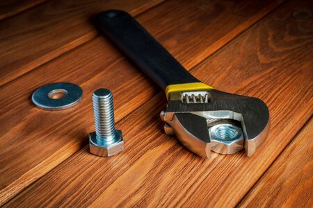 Adjustable spanner with metal nut and bolt on vintage wooden background close upの写真素材