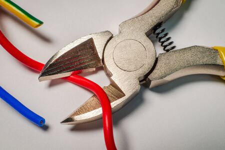 Pliers tool cutting electric wire closeup on a gray backgroundの写真素材