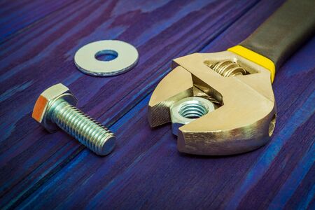 Adjustable spanner with metal nut and bolt on blue vintage wooden background