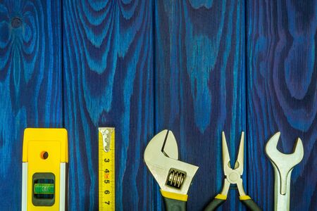 Tools for master builder prepared before work on blue vintage wooden boards with place for advertisingの写真素材