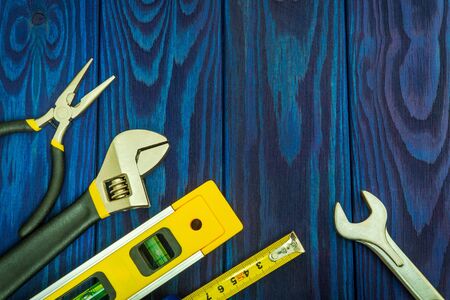 Tools for master builder prepared before work on blue vintage wooden boards with place for advertisingの写真素材