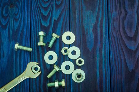 Metal wrench and bolts with nuts on blue vintage wooden background with place for advertisingの写真素材