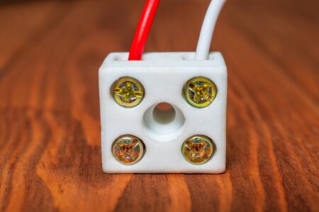 Connection of wires with a plastic clamp and screwdriver on a wooden table close up