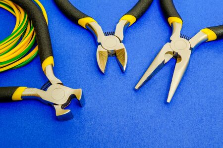 Pliers tool and wires for electrician closeup, service and repairing concept on blue backgroundの写真素材