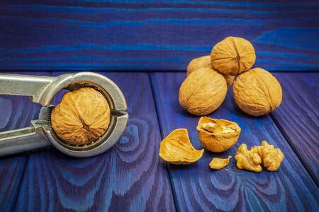 Tongs chop nuts on an old blue vintage table before cooking dessertsの写真素材