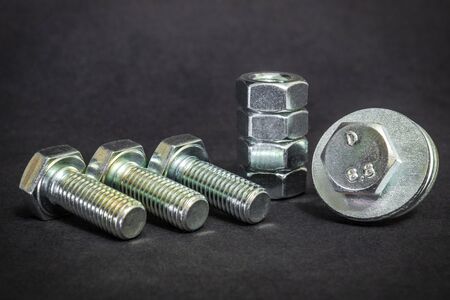 Metal bolts and nuts on a black background are often used in construction