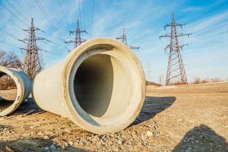 A large concrete pipe for the construction of sewers on the background of high voltage polesの写真素材