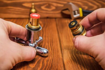 Cruciform hot and cold water main switch of spare parts holding in his hands a master plumber before repairsの写真素材