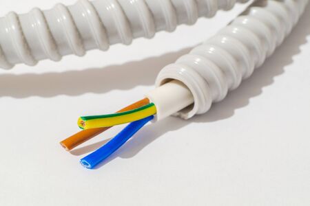 Electric wires of different colors in corrugation on gray background