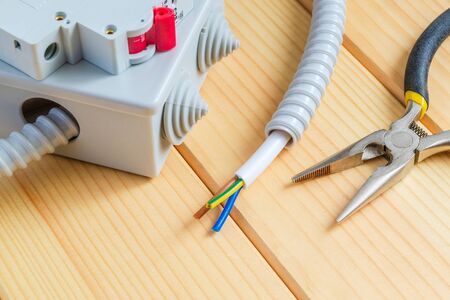 Junction box with wire for and tool repairing electrics in the house on wooden boards