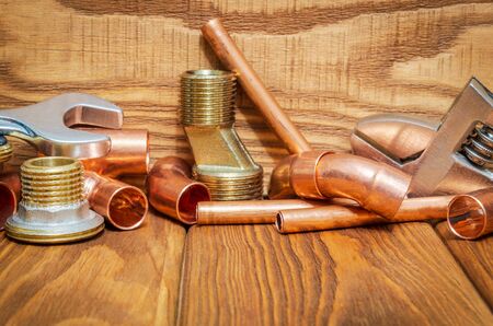 Spare parts with copper and brass accessories for plumbing repair on vintage wooden boardsの写真素材