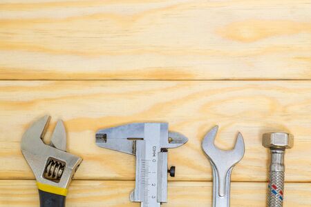 Necessary set of tools and hose for plumbers on wooden boards with space for advertising