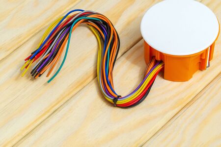 Electrical junction orange box with wires on blue wooden boards usually used in the electric...
